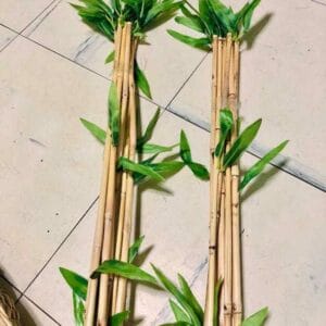 Two bundles of Artificial Bamboo, featuring green leaves, elegantly placed vertically on a tiled floor, make for perfect home decor.