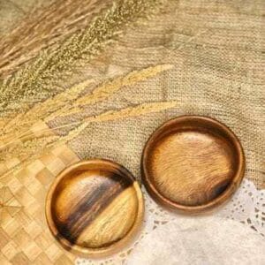 Two SMALL CALABASH BOWLs rest elegantly on a woven surface, complemented by dried grasses and a doily nearby—perfect touches for any home decor inspired by the charm of Dapitan.
