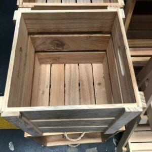 The Wood Crate 1, featuring slatted sides and handles, sits elegantly on a concrete floor, making it an ideal choice for introducing rustic decor into any space.