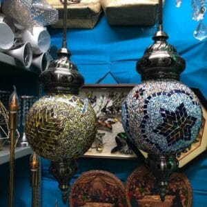 Two ornate Moroccan lamps in a combination of red and blue illuminate the scene against a striking blue backdrop, with decorative plates and items subtly enhancing the vibrant display.