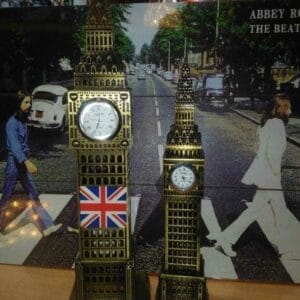 Big Ben Clock Tower Table Decor Clocks big ben clock Two Big Ben Clock Tower Table Decor pieces, one large and one small, serve as charming decor in front of an Abbey Road Beatles album cover.