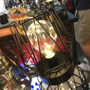 A lit Edison bulb in a small black container illuminates the room, adding a warm glow to the home among other decorative lights, reminiscent of a festive Christmas ambiance.