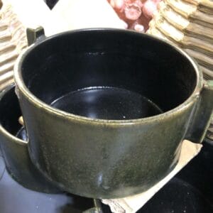 A stunning Black Container - Small with handles from Dapitan graces the table, enhancing the decor among other pottery items.