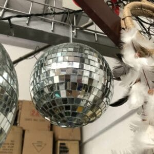 A mirrored disco ball hangs beside a dreamcatcher, adding a touch of quirky decor to the storage area filled with Black Container - Small boxes in Dapitan.