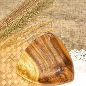 With its charming design, the Soft Edge Triangle Wooden Plate rests on a woven mat adorned with dried grasses and a delicate white doily, adding a touch of Dapitan charm to your home.