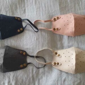The Synthetic Leather Mask is available in black, gray, pink, and beige, elegantly displayed on a light surface to add a touch of home decor style to your everyday essentials.