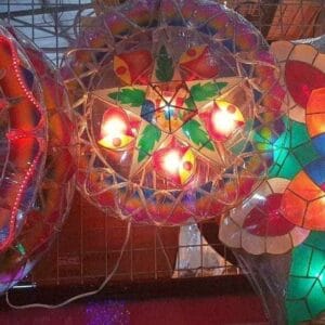 2ft Round Christmas Lanterns, echoing the vibrant home decor of Dapitan, featuring detailed patterns and exquisite lighting, elegantly showcased on a wire rack.