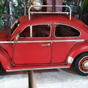 An assorted steel car model in red, featuring a vintage design and a roof rack, is displayed alongside another toy car, adding a charming touch to your home decor reminiscent of Dapitan's eclectic style.
