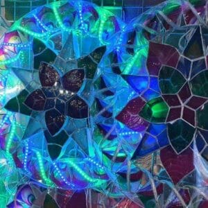 Enhance your home decor with the colorful stained glass art of the Christmas Lantern 30 inches, featuring geometric and floral patterns beautifully illuminated by various lights.