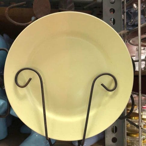 photo_2020-09-03_12-25-50 A Glossy Round Ceramic Plate in a dapitan-inspired yellow hue is elegantly displayed on a black metal stand, adding a touch of unique home decor to the store.