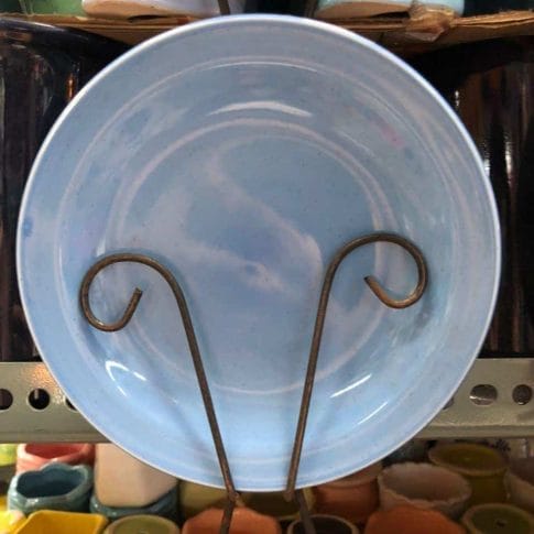 photo_2020-09-03_12-25-52 A Glossy Round Ceramic Plate in blue, a perfect piece of home decor, stands vertically on a shelf amid other colorful pottery treasures from Dapitan.